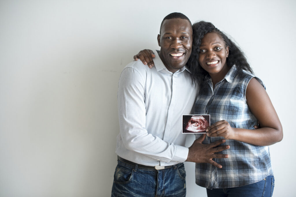 couple smiles and holds ultrasound photo